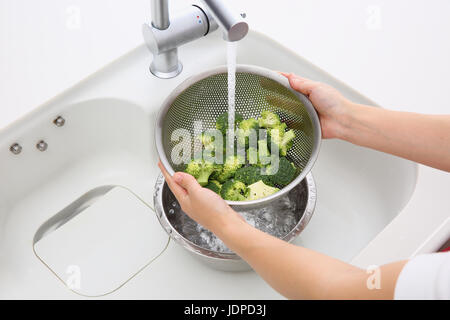 Japanische Frau waschen Brokkoli in der Küche Stockfoto