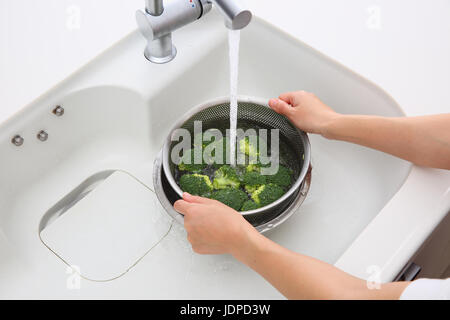 Japanische Frau waschen Brokkoli in der Küche Stockfoto