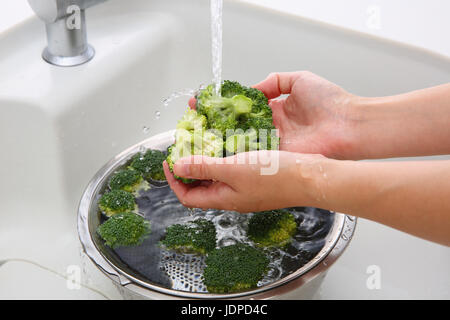 Japanische Frau waschen Brokkoli in der Küche Stockfoto