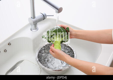 Japanische Frau waschen Brokkoli in der Küche Stockfoto