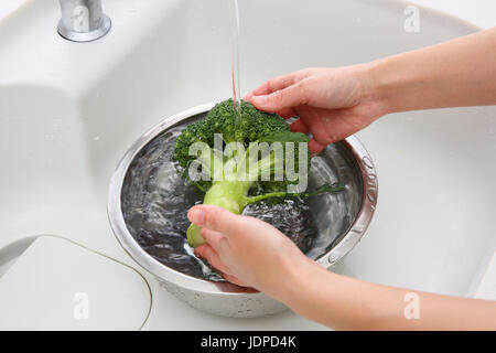 Japanische Frau waschen Brokkoli in der Küche Stockfoto