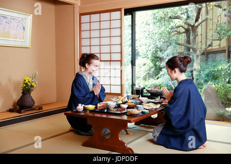 Kaukasische Trägerin Yukata Essen mit japanischer Freund im traditionellen Ryokan, Tokyo, Japan Stockfoto
