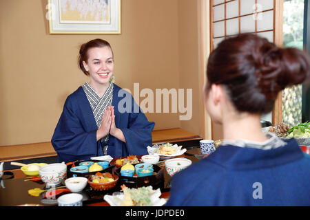 Kaukasische Trägerin Yukata Essen mit japanischer Freund im traditionellen Ryokan, Tokyo, Japan Stockfoto