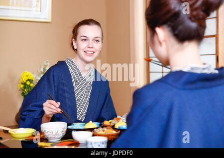 Kaukasische Trägerin Yukata Essen mit japanischer Freund im traditionellen Ryokan, Tokyo, Japan Stockfoto