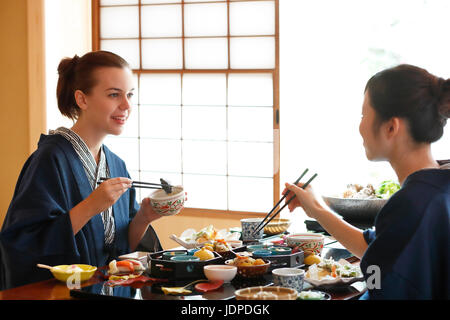 Kaukasische Trägerin Yukata Essen mit japanischer Freund im traditionellen Ryokan, Tokyo, Japan Stockfoto
