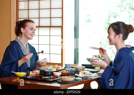 Kaukasische Trägerin Yukata Essen mit japanischer Freund im traditionellen Ryokan, Tokyo, Japan Stockfoto