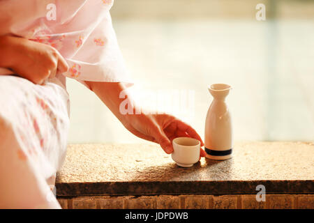 Japanerin mit Sake bei traditionellen Thermalquelle, Tokyo, Japan Stockfoto