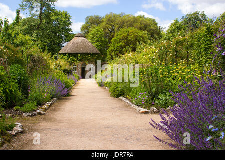 Das 19. Jahrhundert strohgedeckten Round House von wunderschönen Blumenbeeten und Schotterwege, das in der ummauerten Garten in West Dean Gärten in West Sussex umgeben Stockfoto