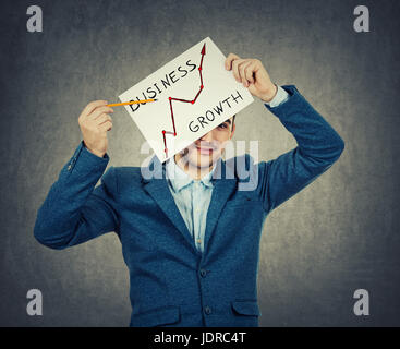 Lächelnd Geschäftsmann mit einem Bleistift wies auf eine steigende Diagramm auf das Papier gezeichnet. Geschäft Wachstum und Fortschritt Symbol isoliert auf graue Wand Zeitmessung Stockfoto