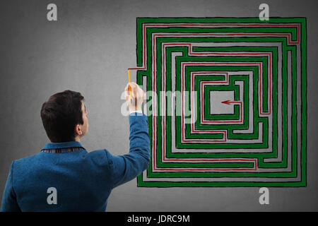 Junger Geschäftsmann mit einem Bleistift in der Hand versuchen, die Lösung eine phantasievolle Quadratmeter Labyrinth zu finden, eine rote Linie zum Erfolg. Rechteck-labyrin