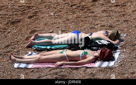 Damen nehmen Sie ein Sonnenbad genießen sie das warme Wetter am Strand in Brighton, East Sussex. Die Temperatur hat 33,9 C (93F) getroffen, am Flughafen Heathrow in West London, so dass es des heißesten Tages im Juni 1976, das Met Office hat gesagt. Stockfoto