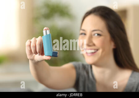 Girl zeigt einen Asthma-Inhalator sitzen auf einer Couch im Wohnzimmer zu Hause Stockfoto