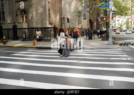 Drei Frauen mit Rädern Gepäck überqueren Zebrastreifen auf der Fifth Avenue in New York City USA Stockfoto