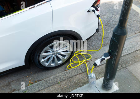 Ein Elektroauto-Ladegerät-Umbau durch Ubitricity: Intelligentes Kabel an einer Straßenlampe, mit dem nun ein Elektroauto von einer Lampenpfosten (in diesem Fall ein Tesla) geladen werden kann. Twickenham UK Stockfoto