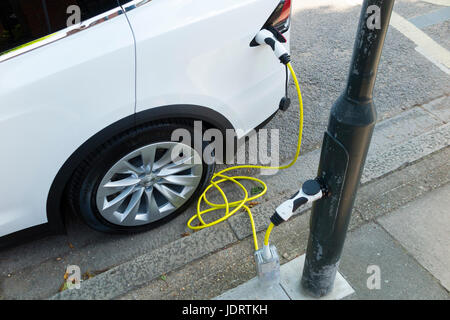 Ein Elektroauto-Ladegerät-Umbau durch Ubitricity: Intelligentes Kabel an einer Straßenlampe, mit dem nun ein Elektroauto von einer Lampenpfosten (in diesem Fall ein Tesla) geladen werden kann. Twickenham UK Stockfoto