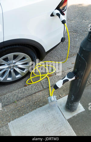 Ein Elektroauto-Ladegerät-Umbau durch Ubitricity: Intelligentes Kabel an einer Straßenlampe, mit dem nun ein Elektroauto von einer Lampenpfosten (in diesem Fall ein Tesla) geladen werden kann. Twickenham UK Stockfoto