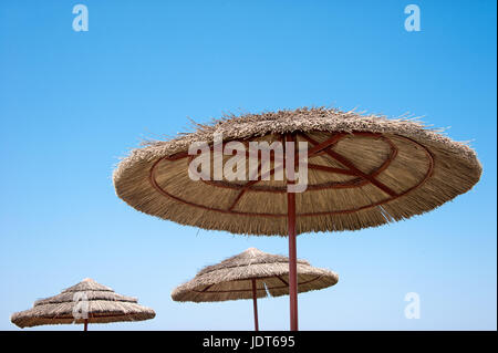 Zuckerrohr-Wicker-Strand-Sonnenschirme schließen gegen den Himmel bei sonnigem Wetter. Die horizontalen Rahmen. Stockfoto