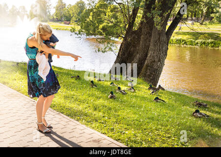 Mutter zeigt Enten auf ihr Baby in der Nähe von Park-Teich Stockfoto