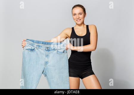 junge schlanke sportliche Frau mit Übergröße Hosen Stockfoto