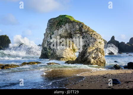 Wellen brechen und Felsbogen befindet sich auf der Küste von North Antrim zwischen Whitepark Bay und Ballintoy in County Antrim-Nordirland Stockfoto