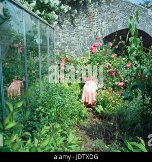 Gilr spielen in Blumen von Gewächshaus Stockfoto