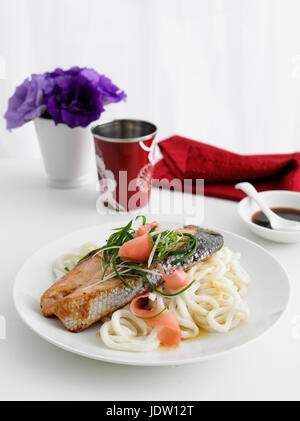 Teller mit Fisch und Pasta auf Tisch Stockfoto