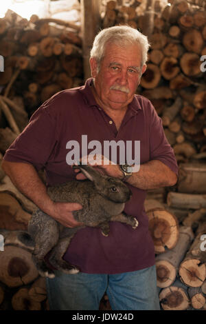 Älterer Mann streicheln Kaninchen im Stall Stockfoto