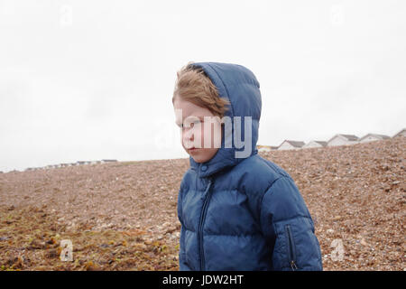 Jungen tragen Parka auf felsigen Strand Stockfoto