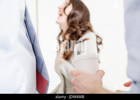 Person, die Kaffee mit Frau lachend im Hintergrund Stockfoto
