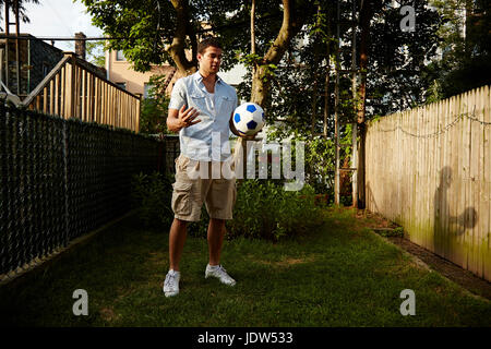 Mann-Betrieb-Fußball im Garten Stockfoto