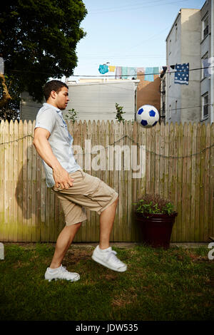 Junger Mann treten Fußball im Garten Stockfoto