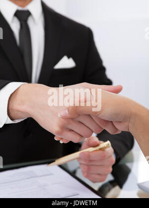 Zugeschnittenes Bild von Geschäftskollegen Händeschütteln am Schreibtisch Stockfoto