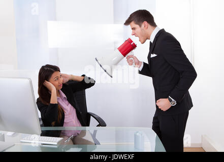 Wütend Geschäftsmann schreien über Megaphon auf Geschäftsfrau im Büro Stockfoto