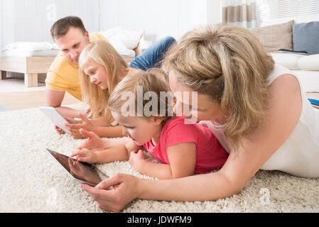 Familie mit Tabletten liegen auf Teppich zu Hause Stockfoto