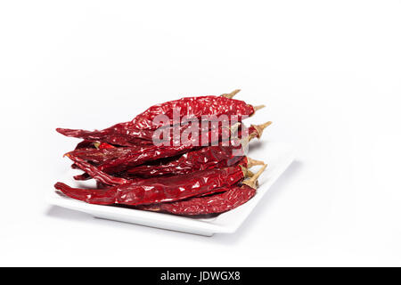 Food Fotografie Foto von getrocknete rote Chilis auf einem Teller isoliert auf weißem Hintergrund. Schöne Haufen Bio rote Chilis mit Textfreiraum Stockfoto