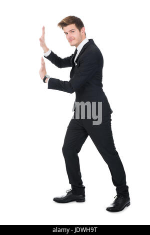 Voller Länge Seitenansicht der Geschäftsmann, die unsichtbare Wand vor weißem Hintergrund schieben Stockfoto