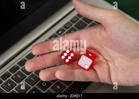 Bild der Geschäftsmann Betrieb rot Spiel Würfel beschnitten, während mit Laptop im Büro Stockfoto