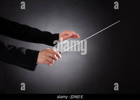 Nahaufnahme des weiblichen Dirigent mit Baton auf schwarzem Hintergrund Stockfoto