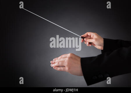 Nahaufnahme des weiblichen Dirigent mit Baton auf schwarzem Hintergrund Stockfoto