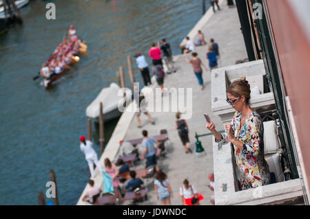 Venedig - 6. Juni 2017.  Eine Frau nehmen einige von ihrer Terrasse während der 43. Vogalonga, nicht kompetitiver Regatta in Venedig gedreht. Stockfoto