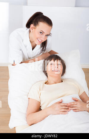 Porträt von glücklich Ärztin trösten senior Frau liegen im Bett in Klinik Stockfoto