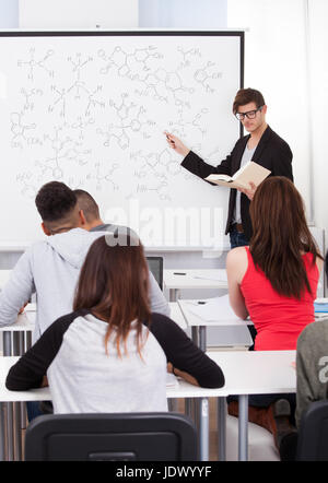 Junge Lehrer unterrichten chemische Formeln für College-Studenten im Klassenzimmer Stockfoto