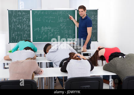 Junge Lehrer Mathematikunterricht zu langweilen College-Studenten im Klassenzimmer Stockfoto