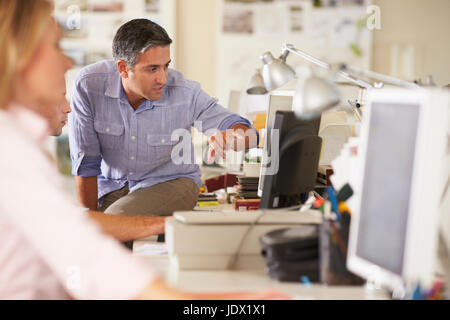 Arbeiter an Schreibtischen In belebten Kreativbüro Stockfoto