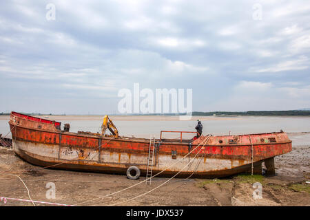 Glasson Dock Estuary & Marina, Lancashire, Großbritannien. Polnische Arbeiter demontieren und verschrotten das zerstörte Fischerboot Mercer. Stockfoto