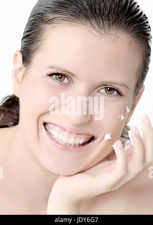 Junge Frau lächelnd mit Creme an den Fingern Stockfoto