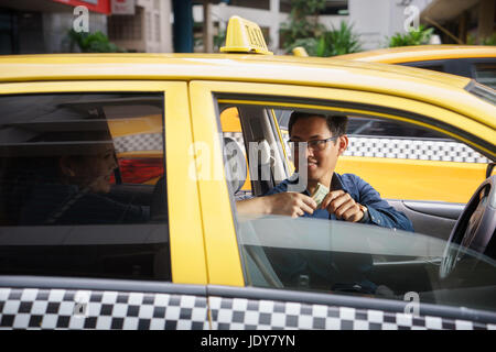 Asiatischer Mann arbeitet als Taxifahrer in gelbes Auto mit weiblichen Kunden bar bezahlen und verlassen Stockfoto