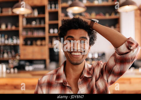 Porträt des jungen glücklich lächelnd in ein Café mit Hand am Kopf hautnah. Junge afrikanische Männchen in einem Café, Spaß zu haben. Stockfoto