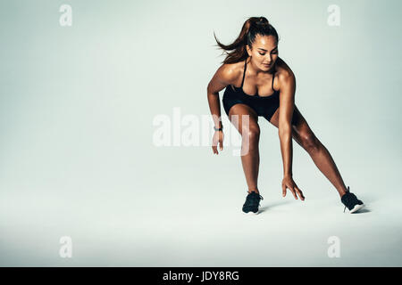 Fitness-Frau, die über grauen Hintergrund läuft. Hispanisches weibliches Model, das im Studio arbeitet. Stockfoto