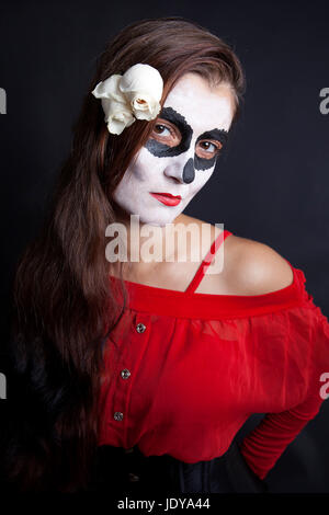 Frau mit Make-up von la Santa Muerte mit weißen Rosen vor schwarzem Hintergrund Stockfoto